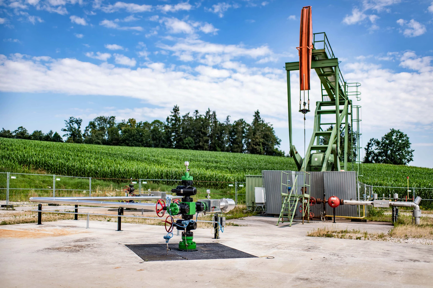 Erdöl-Sonde vor grüner Wiese und blauem Himmel