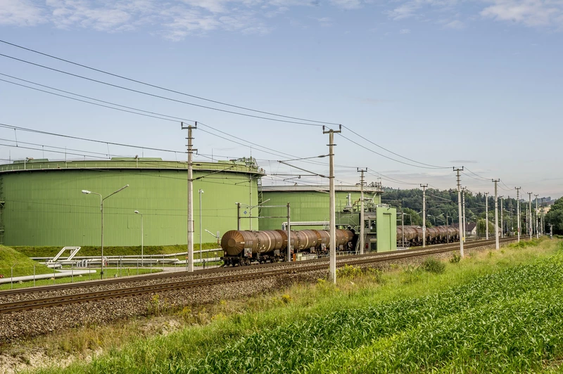 Tanks hinter Bahngleisen und grüner Wiese